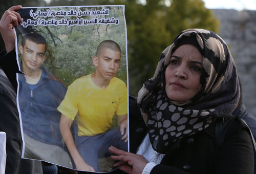 A Palestinian woman holds a placard with pictures of Palestinian attackers from East Jerusalem who were killed by Israeli forces while carrying attacks against Israelis in the recent wave of violence, during a protest on Tuesday (AFP photo)